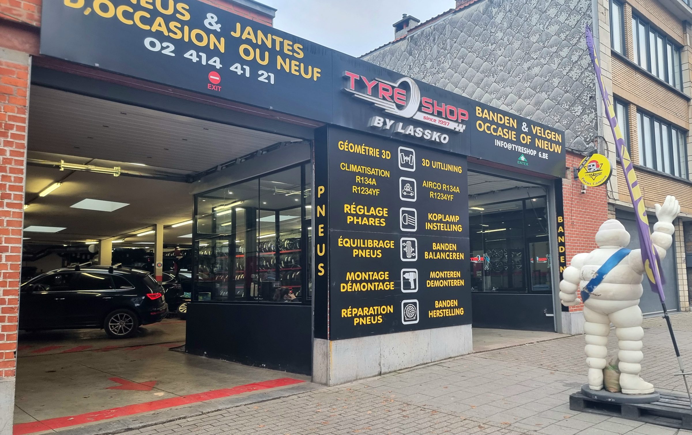 La façade du Tyre Shop chaussée de Mons, avec le panneau des services en français et en néerlandais